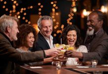 People laughing while clinking glasses at a bar