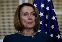 Pelosi’s Wealth SURGES – 16,930% Return? Person standing near American flag indoors