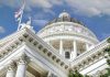 Capitol building dome and flags under a blue sky.