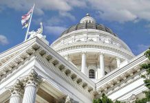 Capitol building dome and flags under a blue sky.