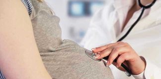 Doctor uses stethoscope on pregnant womans belly.