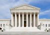 Front view of the Supreme Court building with large columns and steps under a blue sky