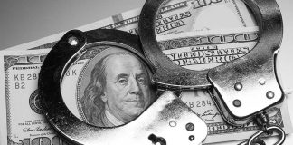 Handcuffs placed over a stack of hundred dollar bills