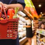 Grocery Chain Defies ICE – Food Runs Ignite Fury Person holding a basket filled with colorful vegetables in a supermarket