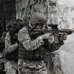 Soldiers in tactical gear advancing through a damaged building