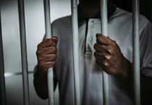 Celebrity PUNCHES Worker – Gets Arrested! Person holding jail cell bars tightly.