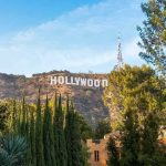 Hollywood sign on hill surrounded by trees and buildings.