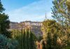 Hollywood sign on hill surrounded by trees and buildings.