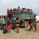 People crowd around and climb into a truck.