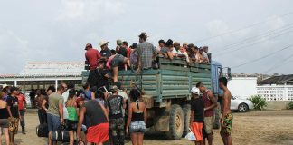 People crowd around and climb into a truck.