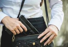 Person placing gun into a handbag.