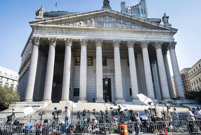 Courthouse facade with media crews setting up outside.