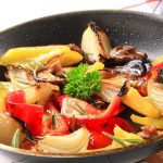 A skillet filled with colorful stir-fried vegetables including onions and bell peppers