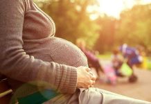 Big Tech SPIED On Woman’s Labor Pregnant woman sitting on a bench in a park during sunset