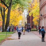 College Blocks ICE – Sexual Predator Shielded Students walking on a campus path surrounded by autumn trees and brick buildings