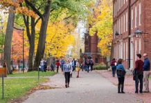 College Blocks ICE – Sexual Predator Shielded Students walking on a campus path surrounded by autumn trees and brick buildings
