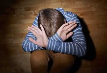 Unthinkable Abuse: Child Eats Cockroach Under Threat A child sitting on the floor with their hands covering their face, expressing distress