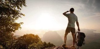 Hiker standing on a rocky outcrop overlooking a valley at sunset