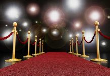 Celebrity Wife TRAPPED By Stalker A red carpet lined with gold stanchions and ropes under bright spotlights