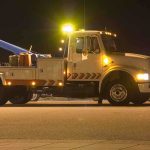 Tow truck with flashing lights parked at night