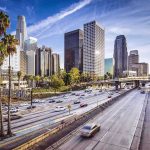 Downtown cityscape with skyscrapers and highway traffic.