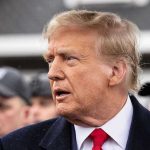 Trump’s Ties Spark Kennedy Center Outrage Man in suit and red tie speaking outside.