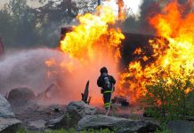 Firefighter battling a large fire with water spray