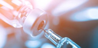 Close-up of a syringe drawing liquid from a vial