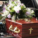 Mom Hauls Daughter’s Corpse Cross-Country Coffin with flower arrangement in a hearse.