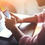 Court Shock: Face ID Can Be Forced Person using a smartphone and laptop at desk.