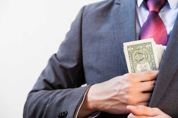 Person in suit putting dollars in jacket pocket.