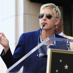 AWKWARD: Ellen Drops $27M After FLEEING America A woman in sunglasses speaking at a podium during an outdoor event