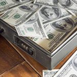 A briefcase filled with hundred dollar bills on a wooden surface