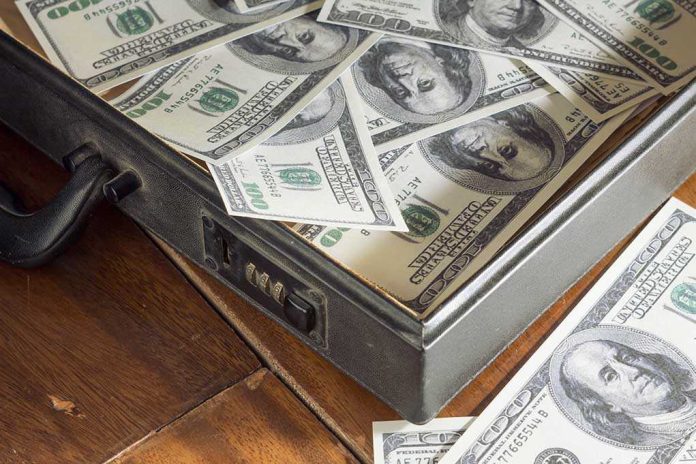 shutterstock_147514376.jpg A briefcase filled with hundred dollar bills on a wooden surface