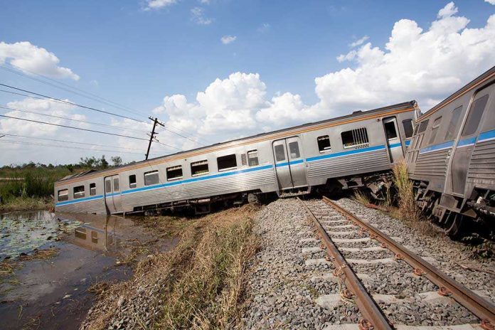 An overturned train on a railway track surrounded by vegetation