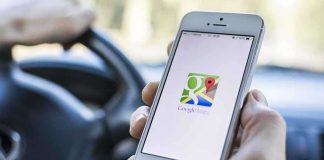 A person holding a smartphone displaying the Google Maps app while driving