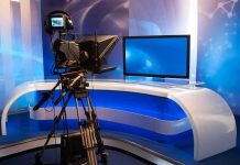 TV studio with camera and empty anchor desk.