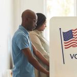 People voting at polling booths with American flag.