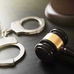 Body in Comforter: Alarming Witness Account Handcuffs and judges gavel on the table.