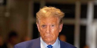 Man in blue suit and striped tie, serious expression.