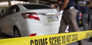 Crime scene tape blocking off white sedan.