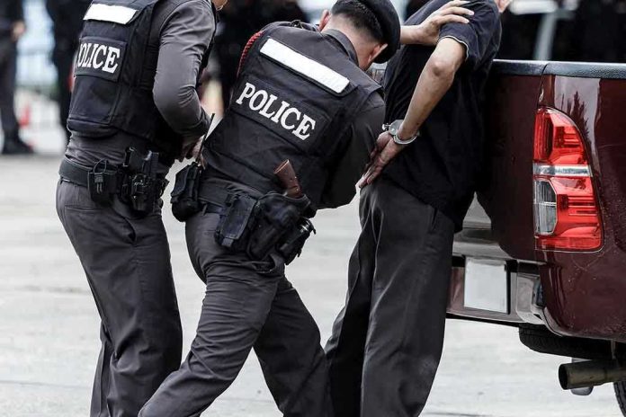 Police officers arresting a handcuffed person.