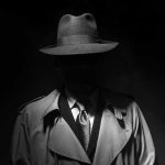 Blues Brother Murder Shocks Hermosa Beach Person in trench coat and fedora, face obscured by shadow.