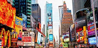 Times Square crowded with people and bright electronic advertisements.
