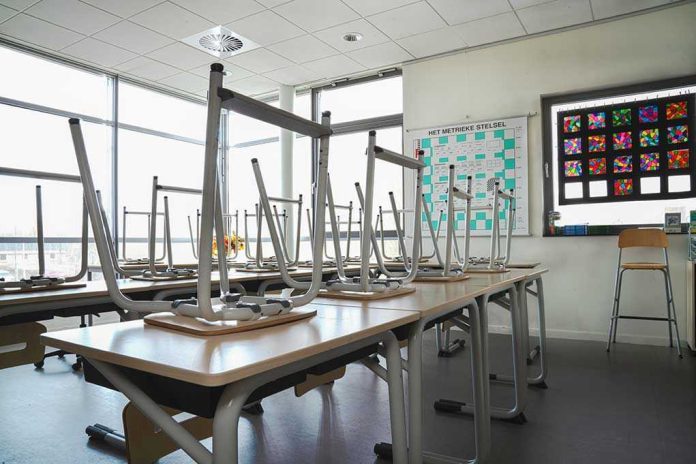 shutterstock_1680256285 Empty classroom with chairs on top of desks.