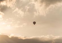 BALLOON Snags Tower—Passengers Hang 1,000 Feet A hot air balloon floating in a cloudy sky during sunset