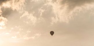 A hot air balloon floating in a cloudy sky during sunset