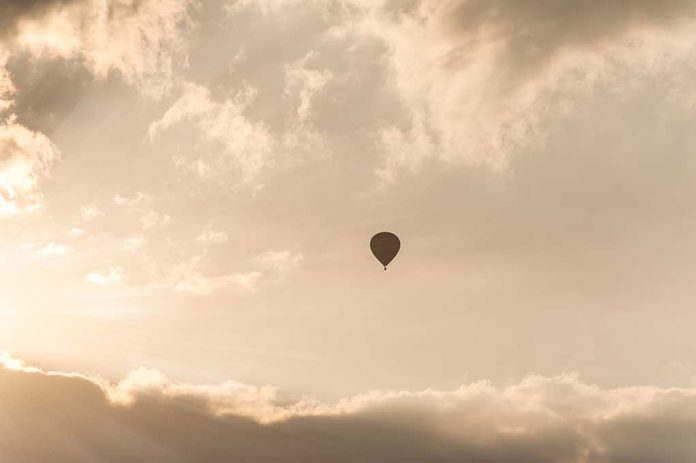 A hot air balloon floating in a cloudy sky during sunset