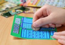 A person scratching off a bingo lottery ticket with a coin