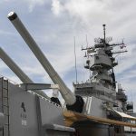 Close-up of a battleships naval guns and superstructure against a cloudy sky